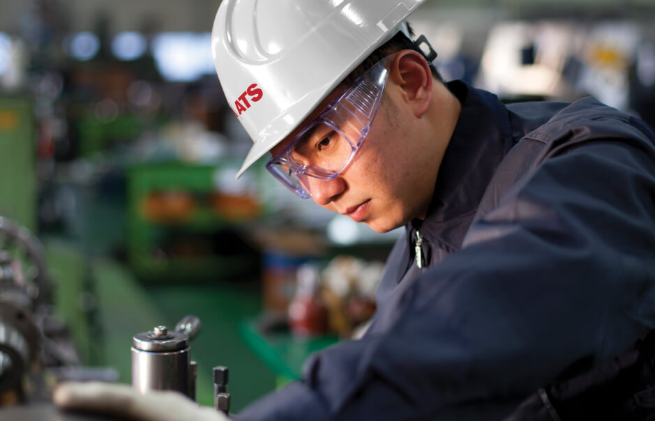 Man in hard hat and protective glasses working with machinery