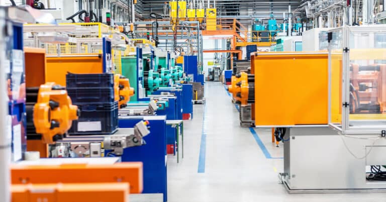 Horizontal image of huge new modern factory with robots and machines producing industrial plastic pieces and equipment.