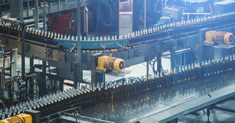 Beer bottles on a conveyor belt, in an industrial factory production line.