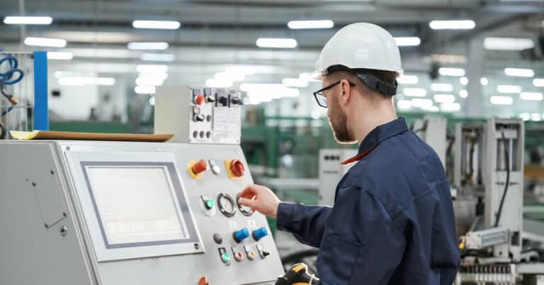 Factory worker operating machinery in a factory wearing PPE.