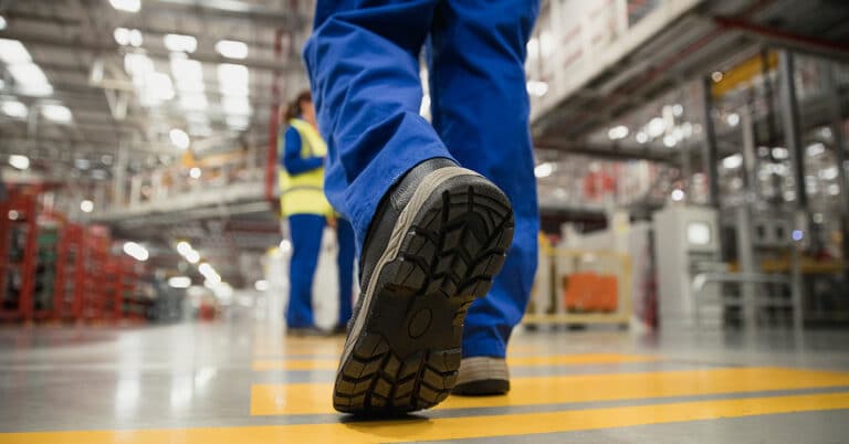 Close-up shot of a workers boot as they walk across the factory floor.