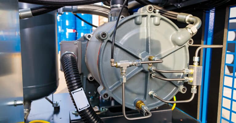 Close-up of an industrial air compressor featuring connecting pipes, hoses, and valves