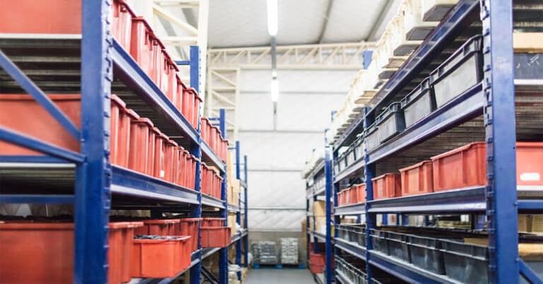 Long shelves factory warehouse with with boxes and containers. Interior of industrial warehouse.