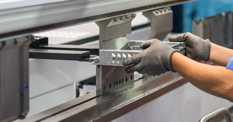 Close up of the hydraulic press. Machine operator is holding the sheet metal parts with safety gloves.